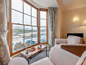 A hotel room with a large window offering a view of the city, a small table with pastries, and two sofas. - 1 Bed in Tenby (oc-fb125) (Tenby)