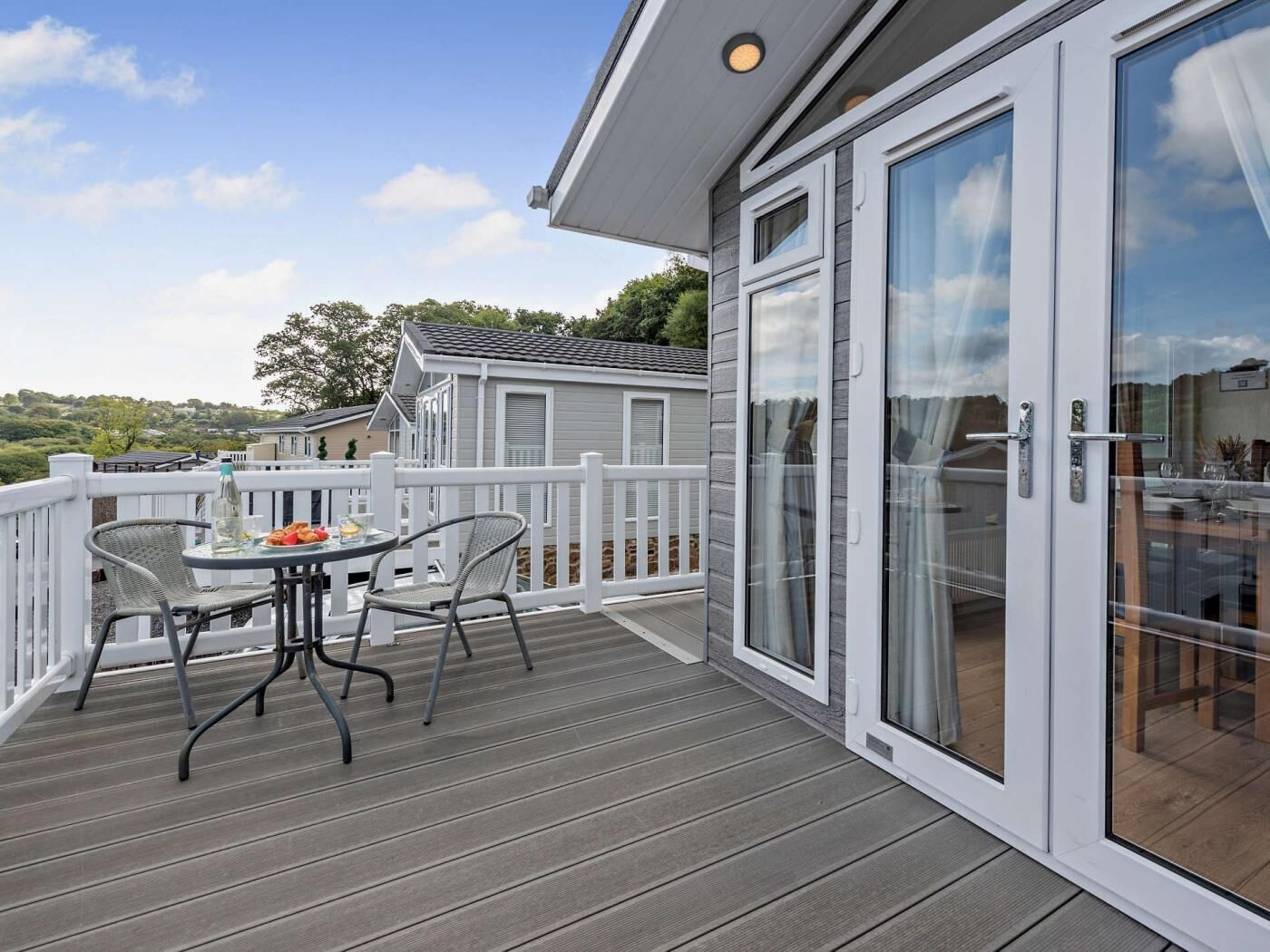 Une terrasse avec une table et des chaises, une porte vitrée et une vue sur le paysage.