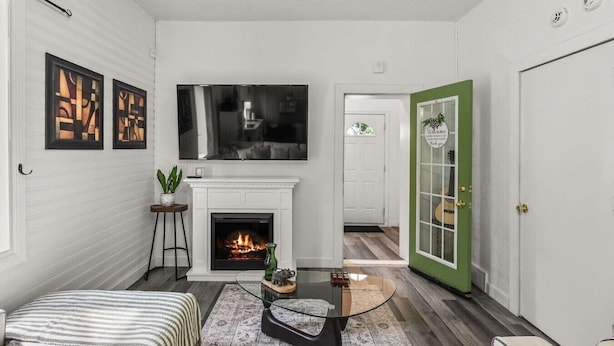 Una sala de estar con chimenea, televisor y puerta verde.