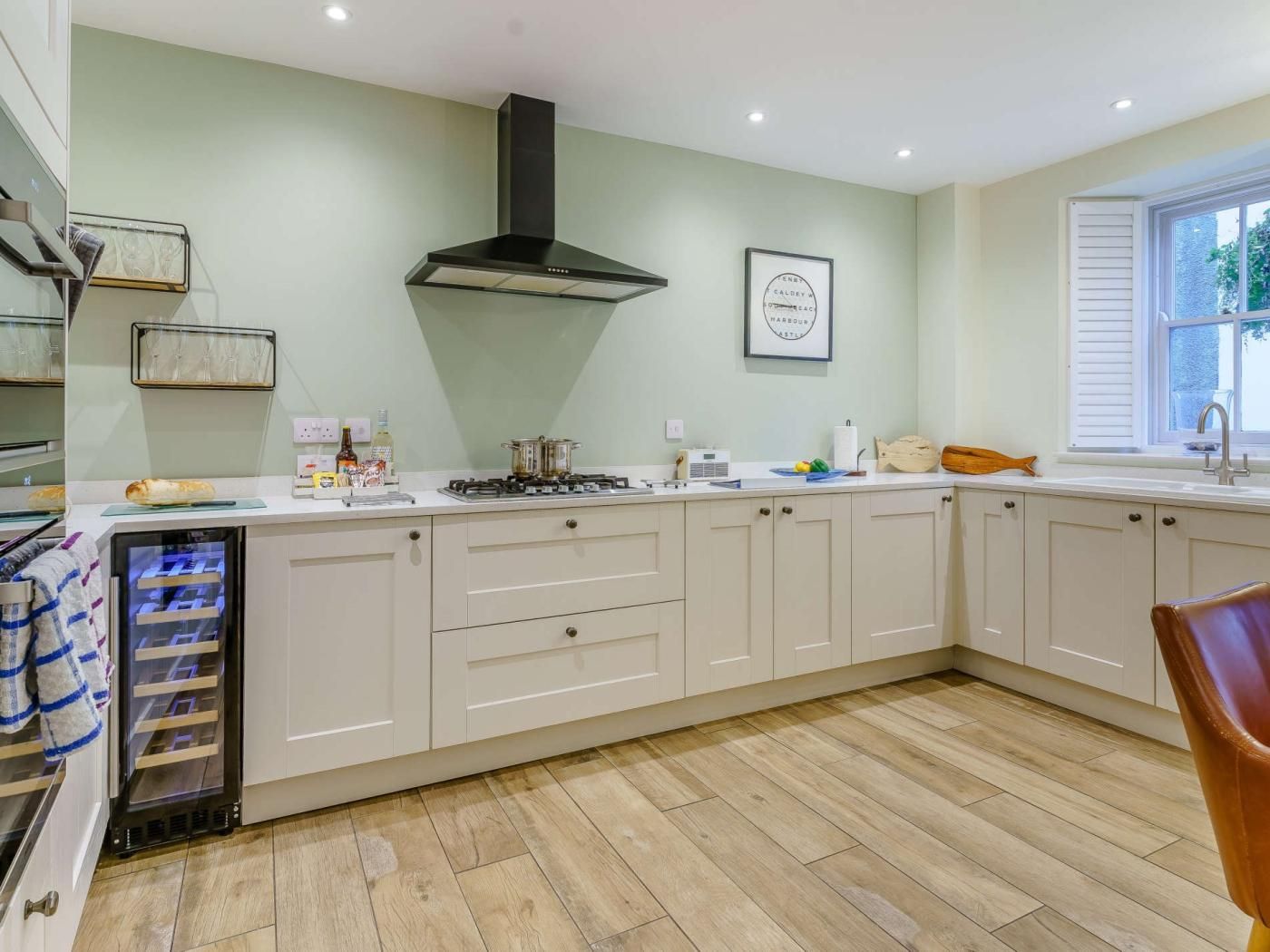A kitchen with a central island, a built-in oven, and a window with shutters.