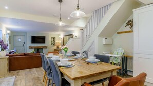 A dining area with a wooden table, chairs, and a staircase. - 4 Bed in Tenby (oc-fb042) (Tenby)