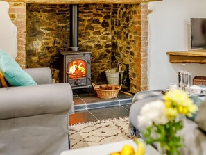 Ein gemütliches Wohnzimmer mit Kamin aus Stein, einer Couch und einem Couchtisch.