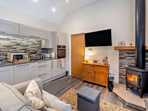 A modern kitchen with a microwave, oven, and a flat-screen TV mounted on the wall. - 1 Bed in Abergavenny (oc-bn408) (Mardy)