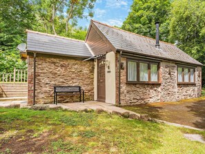 A stone building with a sloped roof, a bench outside, and a small pond. - 1 Bed in Abergavenny (oc-bn408) (Mardy)