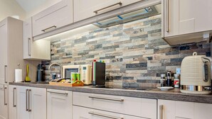 Een moderne keuken met een achterwand van steen, roestvrijstalen apparatuur en lichtkleurige kastjes.