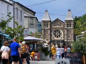 A historic church with a large central window and two towers, surrounded by pedestrians and outdoor seating. - 1 Bed in Abergavenny (oc-bn408) (Mardy)