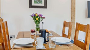 A dining table with plates, a mug, a glass, a vase with flowers, a candle, and a framed picture on the wall. - 1 Bed in Taunton (oc-80693) (North Curry)