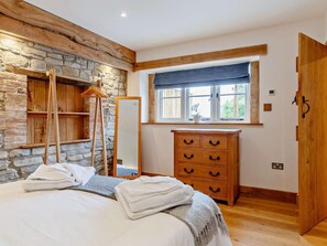 Ein Schlafzimmer mit Steinwand, Holzkommode und einem Bett mit Handtüchern.