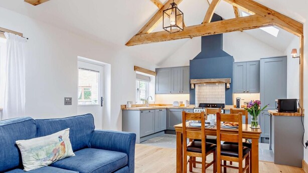 A modern kitchen with grey cabinets, a wooden dining table, and a blue sofa. - 1 Bed in Taunton (oc-80693) (North Curry)