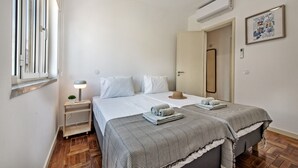 Ein Schlafzimmer mit einem Bett, einem Nachttisch, einer Lampe und einem Fenster.