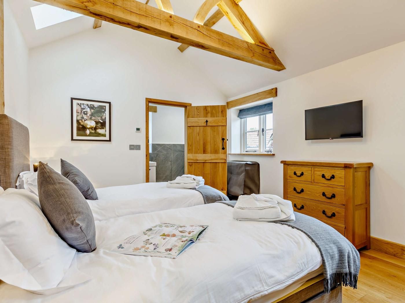 Ein Schlafzimmer mit einem großen Bett, einem Holz-Kopfteil, einem Flachbildfernseher, einer Holzkommode und einem Fenster.