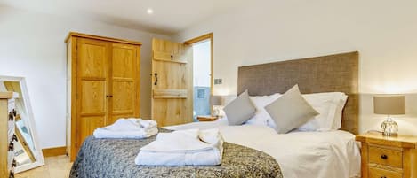 Une chambre à coucher avec un lit, une armoire en bois, un miroir et une table de chevet avec une lampe.