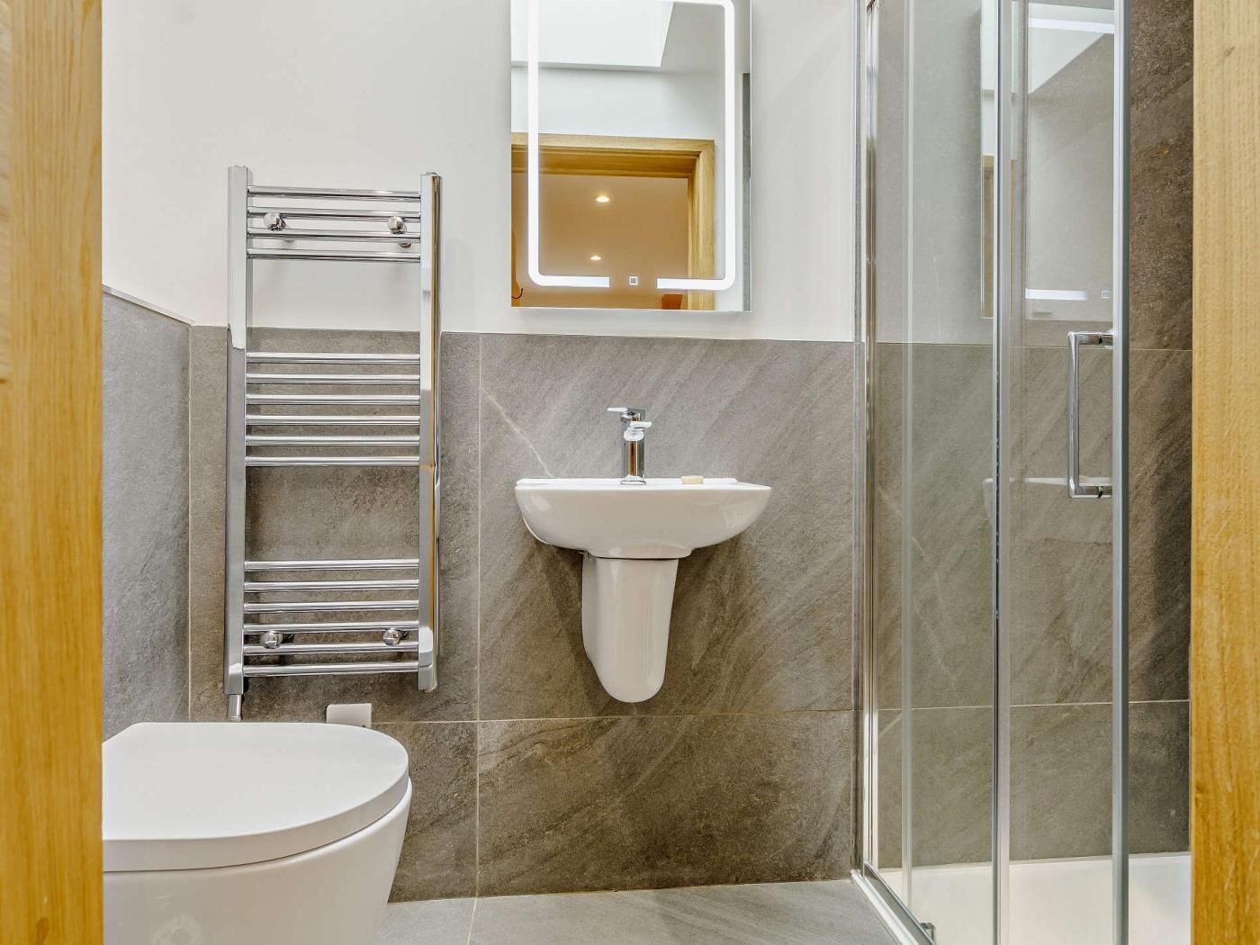 Une salle de bain moderne équipée de toilettes, d’un lavabo, d’une douche à parois de verre et d’un porte-serviettes.