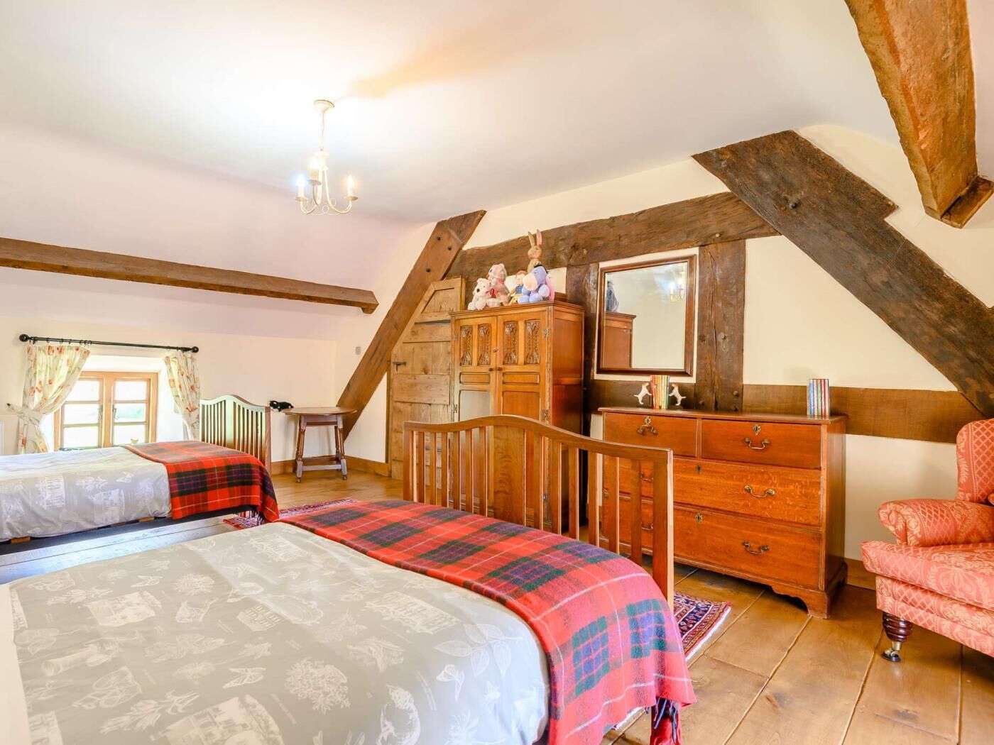 Quarto com duas camas, penteadeira de madeira, uma cadeira e um espelho.