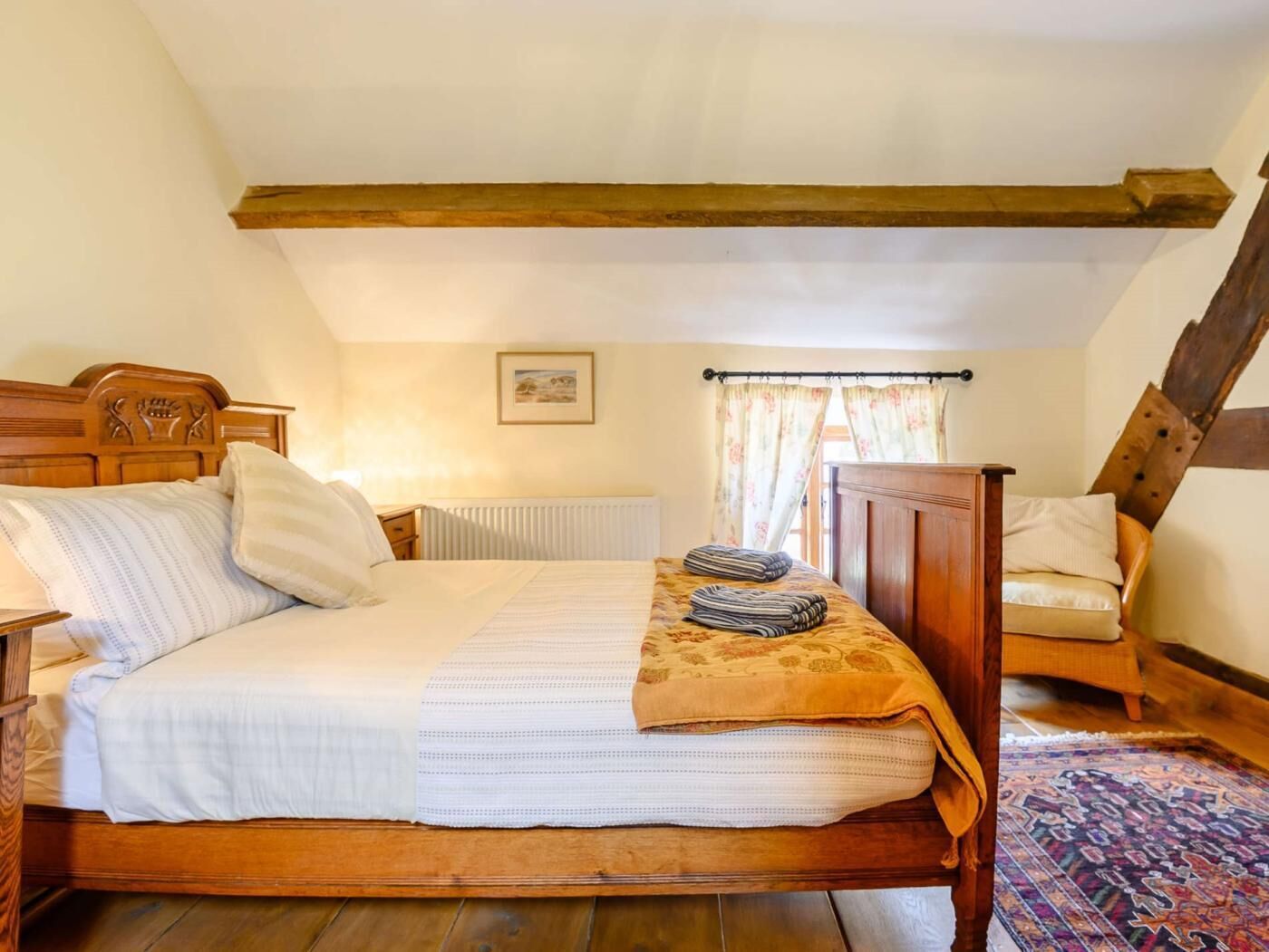 Ein Schlafzimmer mit einem hölzernen Bett, einem Heizkörper, einem Sessel und einem gemusterten Teppich.