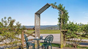 A wooden pergola with a lattice design, a table with chairs, and a view of the countryside. - 2 Bed in Toft Hill (oc-80005) (High Etherley)