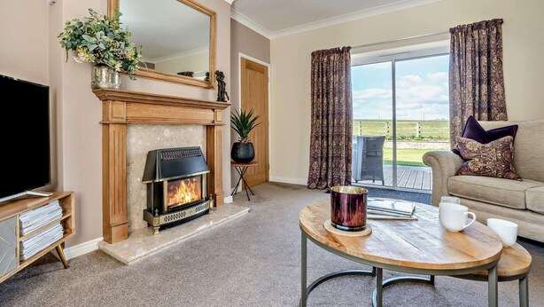 A living room with a fireplace, a television, a sofa, and a table with a cup. - 2 Bed in Toft Hill (oc-80005) (High Etherley)