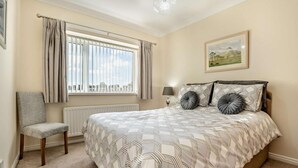 A bedroom with a bed, a chair, a window with curtains, a radiator, a lamp, and a picture on the wall. - 2 Bed in Toft Hill (oc-80005) (High Etherley)