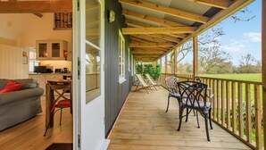 Eine überdachte Veranda mit Esstisch und Stühlen, einer Couch und einer Küchenzeile.