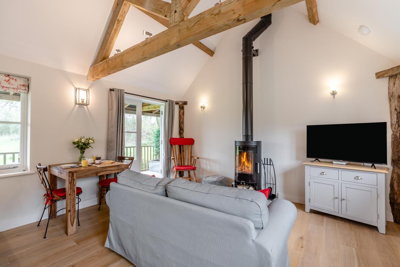 A cozy living room with a sofa, a TV, a fireplace, and a dining area with chairs and a table.