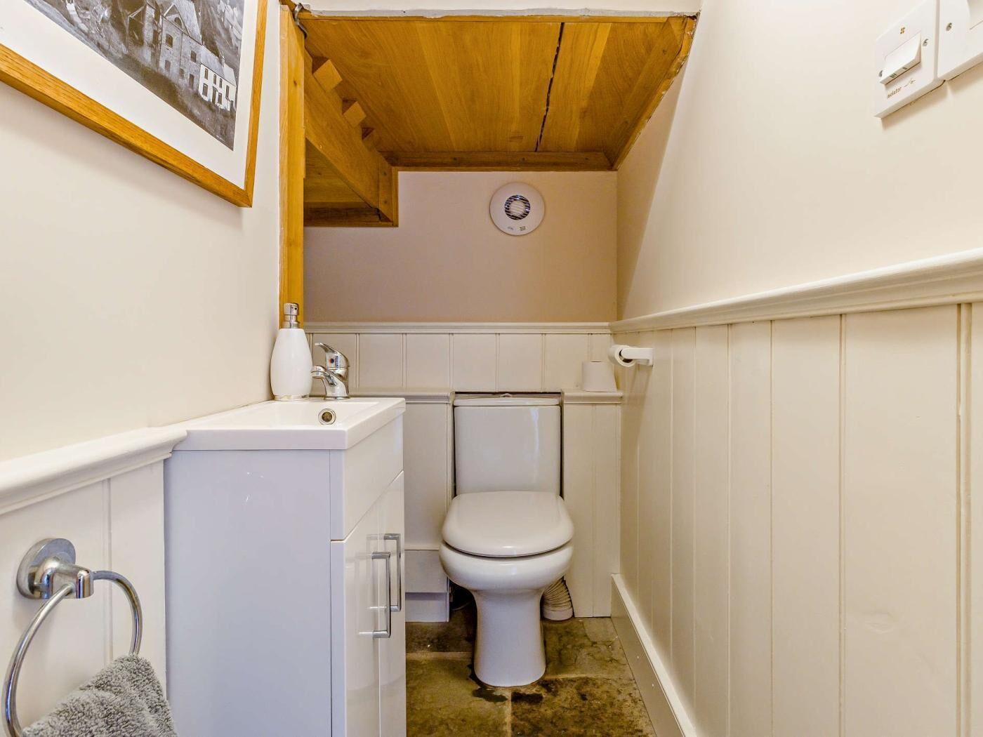 A compact bathroom with a toilet, sink, and a towel rack.