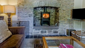 A stone fireplace with a TV on a stand, a sofa, and a lamp. - 4 Bed in Hay-on-wye (oc-bn116) (Hay-on-Wye)