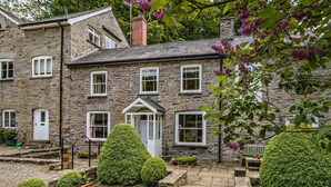 A stone house with a well-maintained garden, a front door, and multiple windows. - 4 Bed in Hay-on-wye (oc-bn116) (Hay-on-Wye)