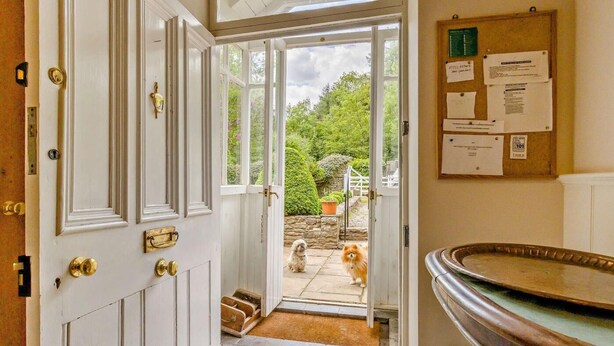 A room with a white door, a small step leading outside, a bulletin board with papers, and a metal sink. - 4 Bed in Hay-on-wye (oc-bn116) (Hay-on-Wye)