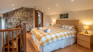 A bedroom with a stone wall, a wooden bed, a nightstand, and a staircase. - 1 Bed in Ystradgynlais (oc-bn046) (Ystradgynlais)