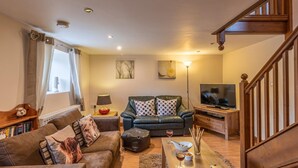 A living room with a sofa, a coffee table, a TV, and a staircase. - 1 Bed in Ystradgynlais (oc-bn046) (Ystradgynlais)