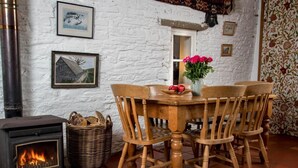 Un interior rústico con chimenea, mesa de comedor de madera, sillas y una cesta de pan.