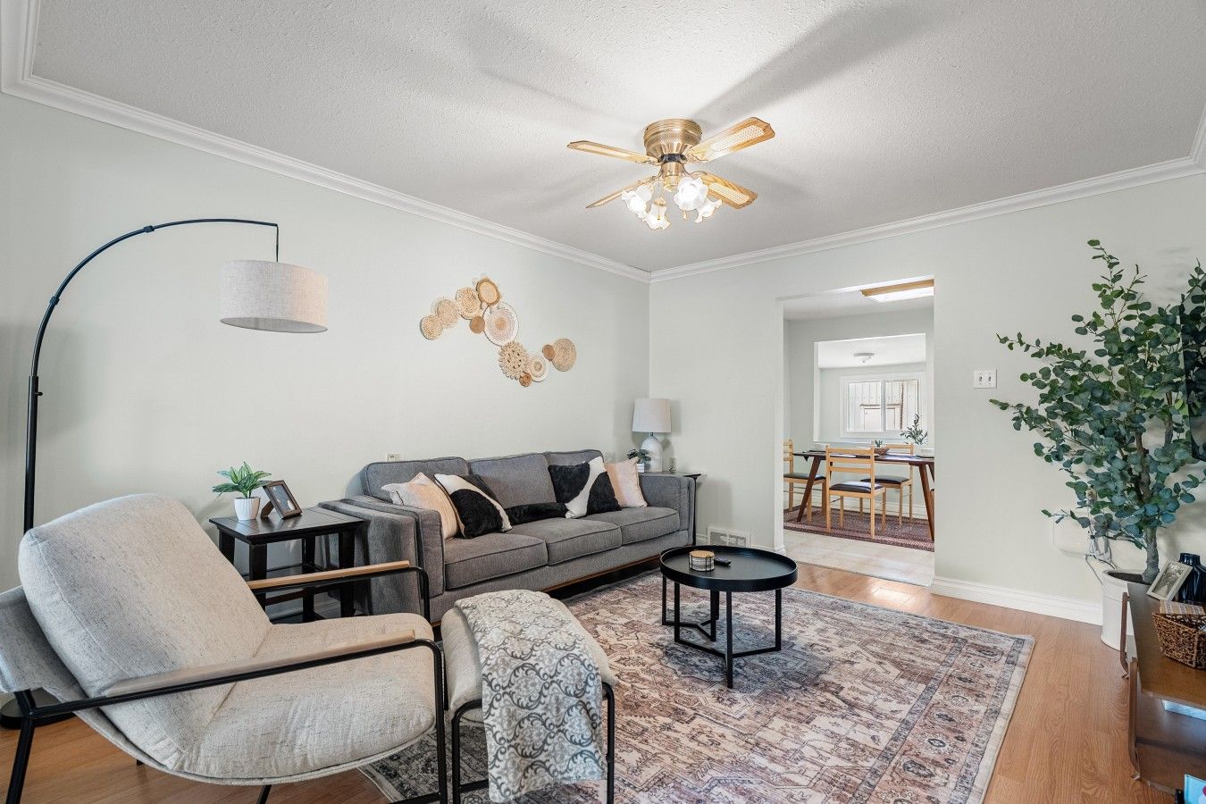 A living room with a sofa, armchairs, a coffee table, a floor lamp, and a ceiling fan.