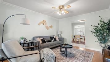 A living room with a sofa, armchairs, a coffee table, a floor lamp, and a ceiling fan.