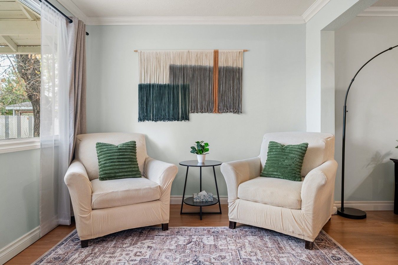 A room with two armchairs, a small table with a plant, and a patterned rug.