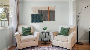 A room with two armchairs, a small table with a plant, and a patterned rug.
