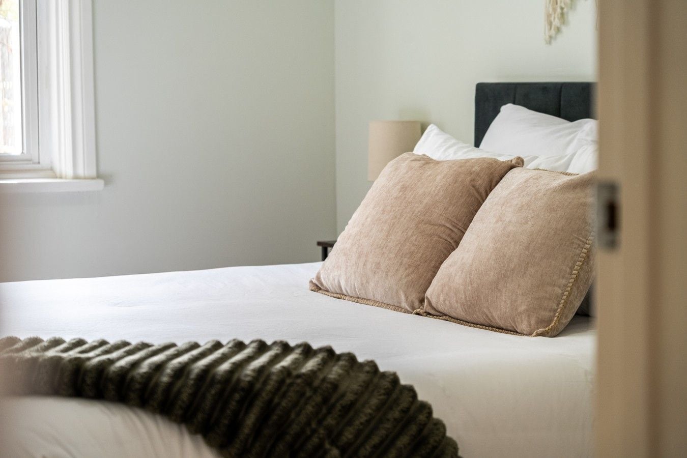 A bed with two pillows, a bedside lamp, and a window.