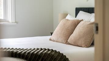 A bed with two pillows, a bedside lamp, and a window.