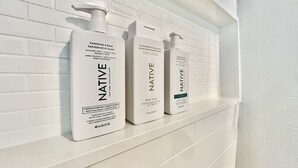Three white bottles of Native body wash on a white tiled shelf. - The Badlands Basecamp (Drumheller)