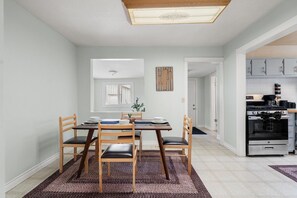 A dining area with a table, chairs, and a view into the kitchen. - The Badlands Basecamp (Drumheller)