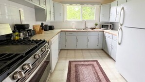 A kitchen with white cabinets, a stove, a microwave, and a refrigerator. - The Badlands Basecamp (Drumheller)
