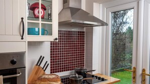 A kitchen with a bread loaf, a pot on the stove, and a red rotary dial telephone. - 2 Bed in Brecon (oc-bn181) (Talybont-on-Usk)