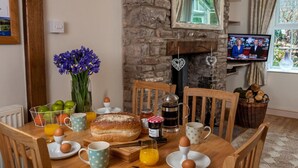 A cozy dining area with a stone fireplace, a television, and a table set for breakfast. - 2 Bed in Brecon (oc-bn181) (Talybont-on-Usk)