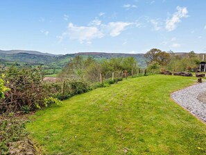 A grassy outdoor area with a fence, a stone path, and a view of distant hills. - 1 Bed in Crickhowell (oc-bn126) (Tretower)