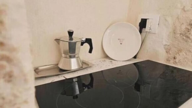 A kitchen with a black induction cooktop, a coffee maker, and a white plate on the counter. - Villa Trullo Septis – Authentic Puglia Amid Olive Trees and Relaxation (Puglia)