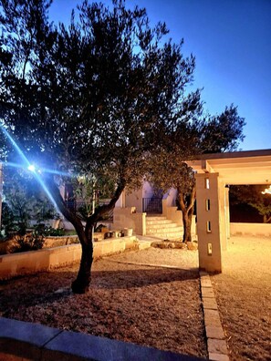 A tree-lined pathway leading to a building with a covered entrance and a staircase. - Villa Trullo Septis – Authentic Puglia Amid Olive Trees and Relaxation (Puglia)