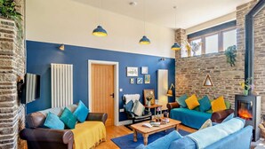 Un salon avec un mur en pierre, une cheminée et des meubles bleus et bruns.