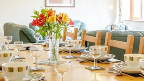 A dining table set for four with white plates, clear glasses, and a vase with flowers. - 5 Bed in Brecon (oc-bn358) (Llyswen)