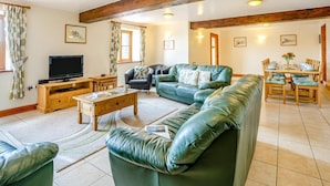 A living room with a sofa, a TV, a dining table set, and a fireplace. - 5 Bed in Brecon (oc-bn358) (Llyswen)
