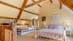 A bedroom with a sloped ceiling, exposed wooden beams, a bed with a metal frame, a nightstand, and a wall-mounted lamp. - 9 Bed in Brecon (oc-bn222) (Sennybridge)