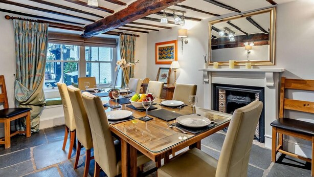 A dining room with a wooden table, chairs, and a fireplace. - 5 Bed in Cartmel (oc-80332) (Cartmel)